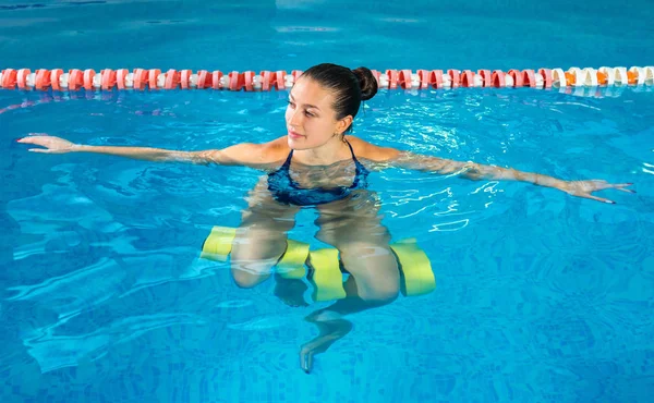 Jonge vrouw doet water aerobics in overdekt zwembad, sportief concept — Stockfoto