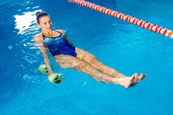 Νεαρή γυναίκα κάνει αερόμπικ νερού στην εσωτερική πισίνα, αθλητική έννοια — Φωτογραφία Αρχείου