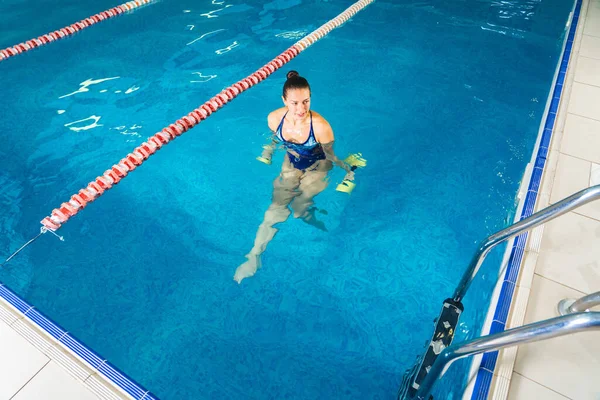 Mladá žena dělá vodní aerobik ve vnitřním bazénu, sportovní koncept — Stock fotografie