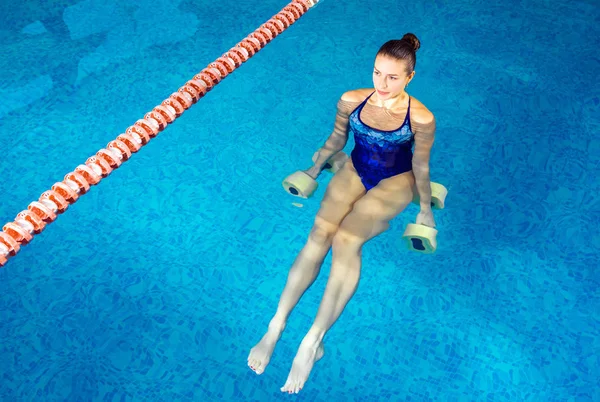 Mujer joven haciendo aeróbic acuático en piscina cubierta, concepto deportivo —  Fotos de Stock
