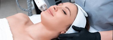 Genç bir kadın kozmetoloji kliniğinde lazer tedavisi görüyor.