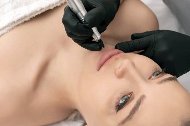 Kozmetik uzmanı dudaklarına kalıcı dövme uyguluyor.