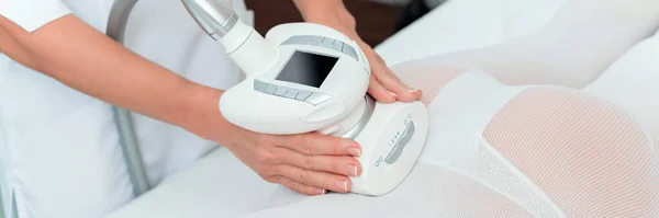 Woman in special white suit getting anti cellulite massage in a spa salon. LPG, and body contouring treatment in clinic.