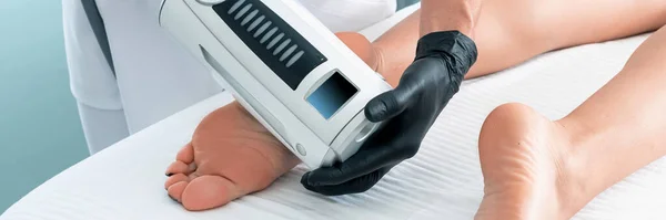 Cosmétologue en gants de caoutchouc faisant des endosphères thérapie sur les pieds féminins — Photo