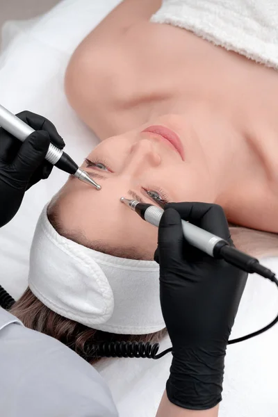 Cosmetología. Hermosa mujer en la clínica de spa recibiendo estimulante tratamiento facial eléctrico de terapeuta. Primer plano de la cara femenina joven durante la terapia de microcorriente — Foto de Stock