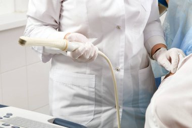 Cropped view of gynecologist holding transvaginal ultrasound wand to exam a woman clipart