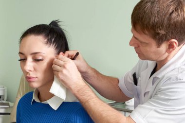 Güzel bir kadının kulak muayenesi yapan ilgili bir doktor.