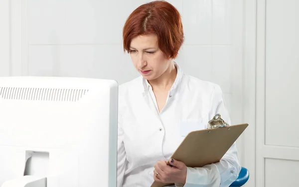 Professional doctor with clipboard near modern ultrasound machine in clinic — 스톡 사진