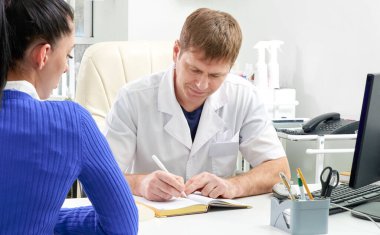 Doktor ofisinde genç bir bayana danışıyor.