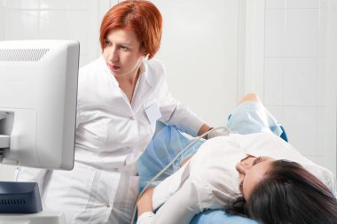 gynecologist holding transvaginal ultrasound wand after examining a woman and showing results on a screen clipart