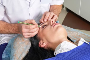  Estetik ameliyattan önce düzeltme çizgileri olan estetik cerrah ve genç kadın, gözlerin üzerine çizgiler çiziyor.