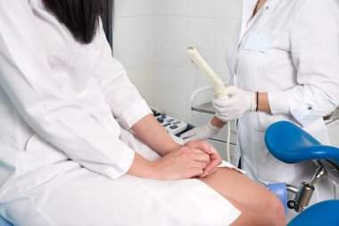 Jinekolog, bir kadını muayene etmek ve değnekle transvajinal ultrason yapmaya hazır.