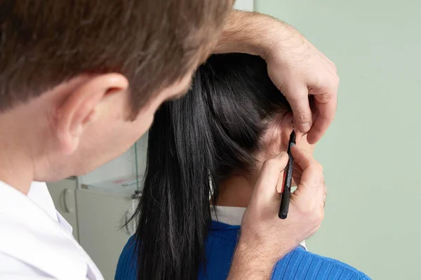 Cirujano plástico examina el oído del paciente antes de la cirugía plástica —  Fotos de Stock