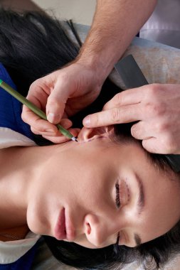 Plastic surgeon examines ear of patient before plastic surgery clipart