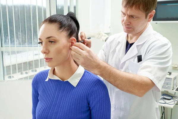 Plastischer Chirurg untersucht Ohr von Patientin vor Schönheitschirurgie — Stockfoto