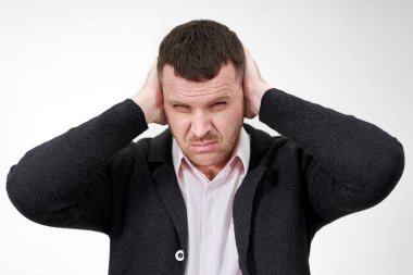 Gri arka planda elleri olan genç işadamı kulaklarını kapatıyor