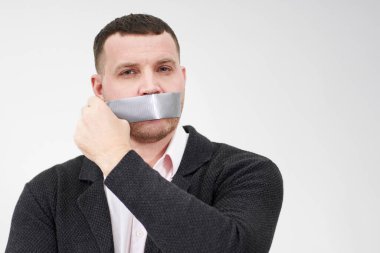İş adamı ağzını kapatan bir bant parçasını çıkarıyor.