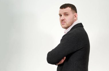 Gri arka planda kollarını kavuşturmuş zarif genç iş adamının yan görüntüsü