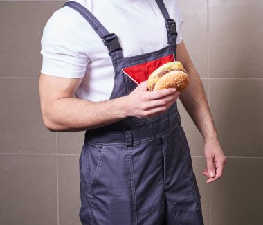 Öğle arasında üniformalı bir işçinin hamburger yediği görüntüler.