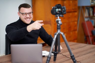 Adam çevrimiçi takipçiler için tripodla video blogu çekiyor. Sosyal medyada, Nüfuz Edici, yeni teknoloji ve internet konsepti