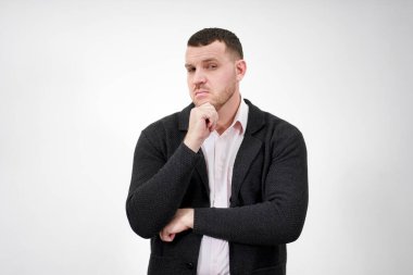 Gri arka planda duran yakışıklı, dalgın genç adam.