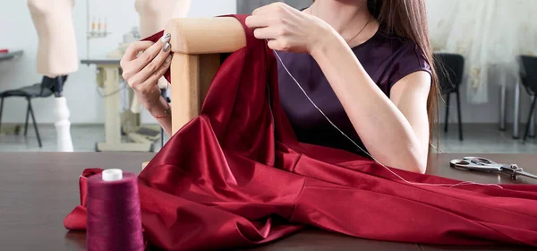 Cropped view of Beautiful young dressmaker in workroom sewing red dress in tailor studio or atelier shop — Stock Photo, Image