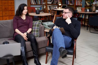 Genç hasta, özel ofisinde notlar alan terapistiyle konuşuyor.