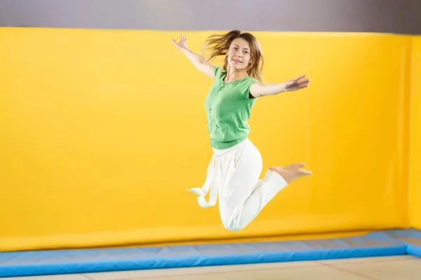 Mujer joven saltando y rebotando en un trampolín en el centro deportivo —  Fotos de Stock