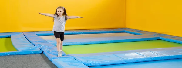 Feliz niña sonriente saltando en el trampolín interior en el centro de entretenimiento — Foto de Stock