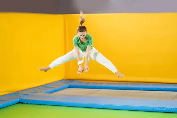 Chica joven saltando en un trampolín en el centro deportivo —  Fotos de Stock