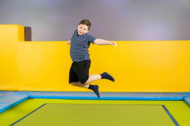 Çocuklar için spor merkezinde trambolinde zıplayan şişman, sevimli bir çocuk.