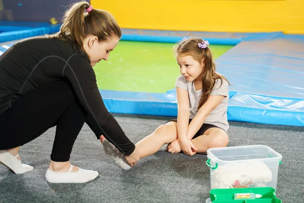 Mädchen hat Schmerzen im Knöchel und holt sich Hilfe nach Sprung auf Trampolin — Stockfoto