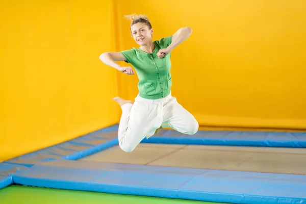 Mujer joven saltando y rebotando en un trampolín en el centro deportivo —  Fotos de Stock