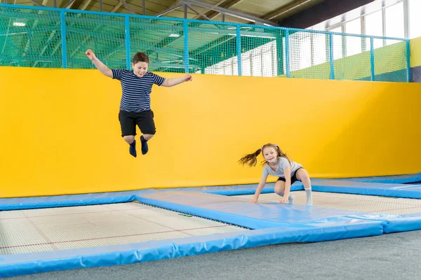 Happy smiling small kids jumping on indoors trampoline in entertainment center — Stock Photo, Image