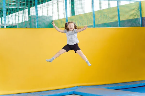 Happy little girl jumping on trampoline in fitness center — Stock Photo, Image