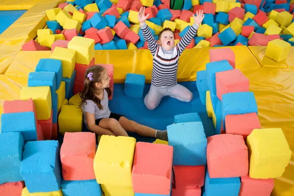 Niños jugando con cubos suaves en la piscina seca en el centro de juego. parque infantil con bloques de espuma en el club de trampolín — Foto de Stock