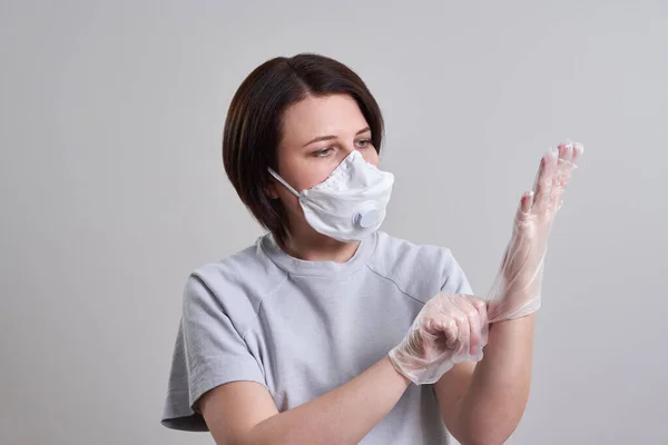 Молодая женщина в маске для защиты от коронавируса на сером фоне с копировальным пространством — стоковое фото