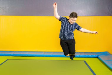 Çocuklar için spor merkezinde trambolinde zıplayan şişman, sevimli bir çocuk.