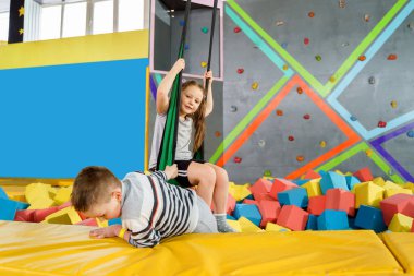 Oyun merkezindeki kuru havuzda yumuşak küplerle oynayan çocuklar. Trambolin kulübünde köpük blokları olan oyun alanı