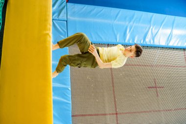 Spor merkezindeki trambolin parkında atlayan genç çocuk. 