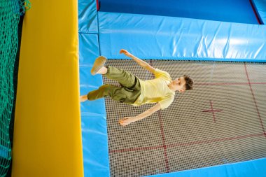 Spor merkezindeki trambolin parkında atlayan genç çocuk. 