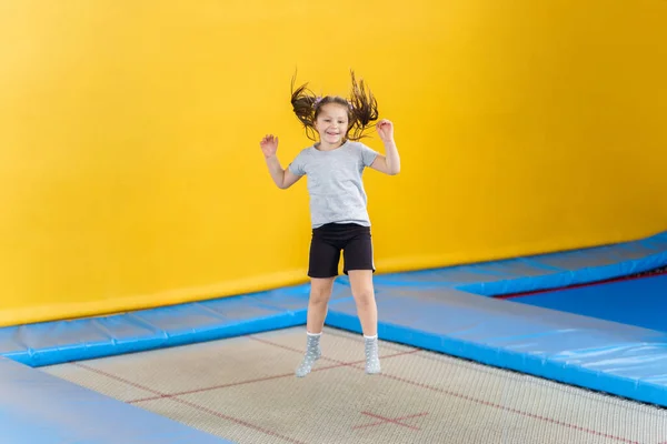 Glückliches kleines Mädchen springt auf Trampolin im Fitnesscenter — Stockfoto