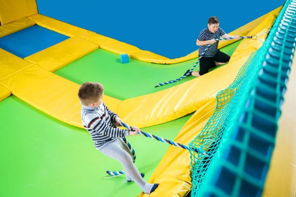 Kids playing in trampoline center jumping and climbing with rope — Stock Photo, Image