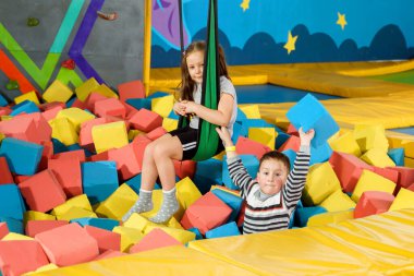 Oyun merkezindeki kuru havuzda yumuşak küplerle oynayan çocuklar. Trambolin kulübünde köpük blokları olan oyun alanı