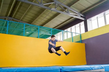 Çocuklar için spor merkezinde trambolinde zıplayan şişman, sevimli bir çocuk.