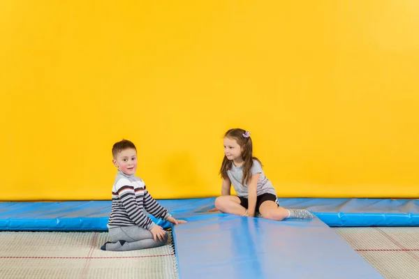 Happy uśmiechnięte małe dzieci skaczące na trampolinie wewnątrz w centrum rozrywki — Zdjęcie stockowe