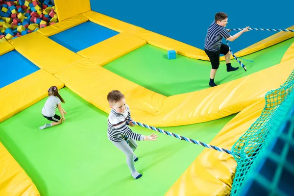 Kids playing in trampoline center jumping and climbing with rope — Stock Photo, Image