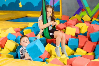 Oyun merkezindeki kuru havuzda yumuşak küplerle oynayan çocuklar. Trambolin kulübünde köpük blokları olan oyun alanı