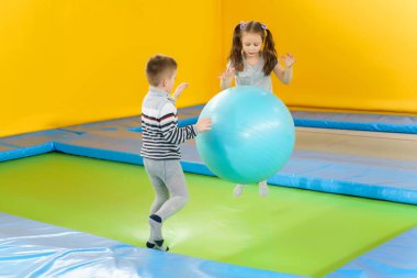 Eğlence merkezinde trambolinde zıplayan mutlu, küçük çocuklar.