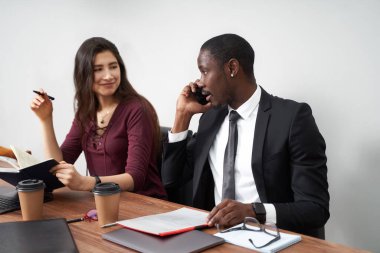 Modern ofiste birlikte çalışan genç ve mutlu iş adamları, çok ırklı takım çalışması. Akıllı telefondan arayan adam.
